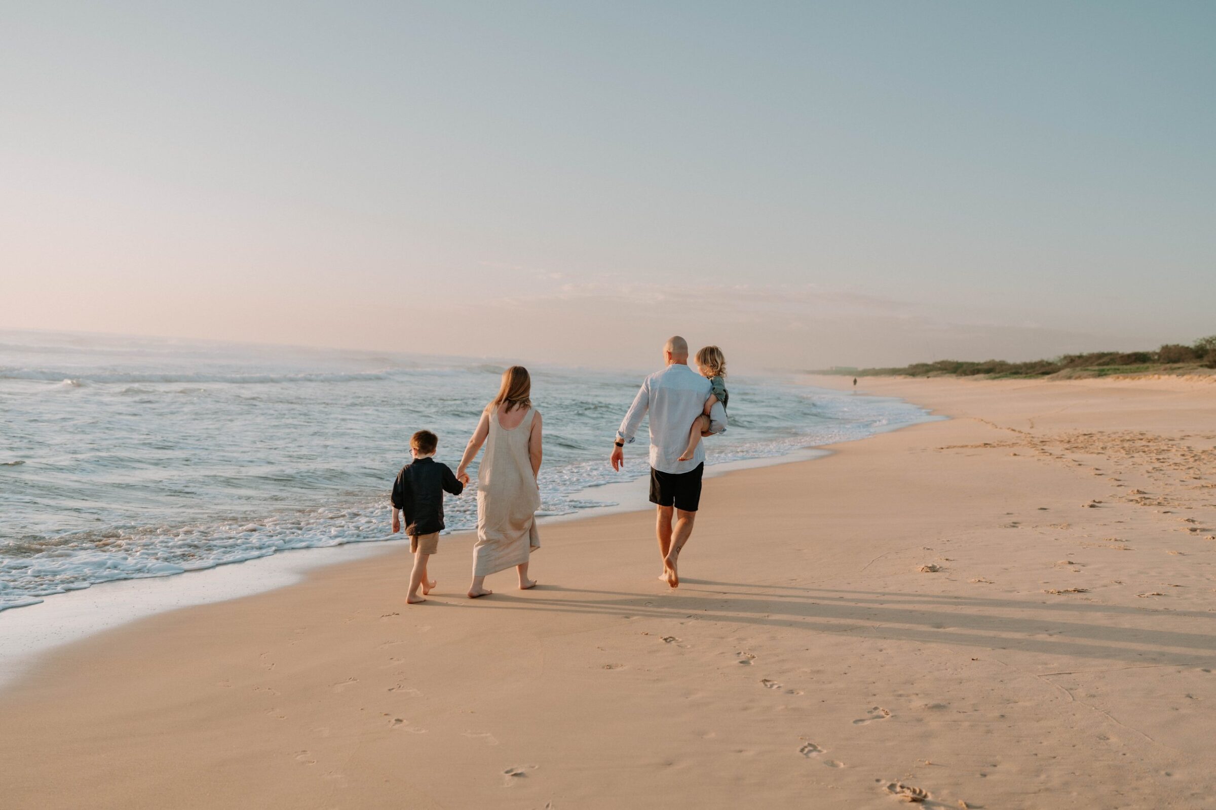 Family walking along a Sunshine Coast beach at sunset